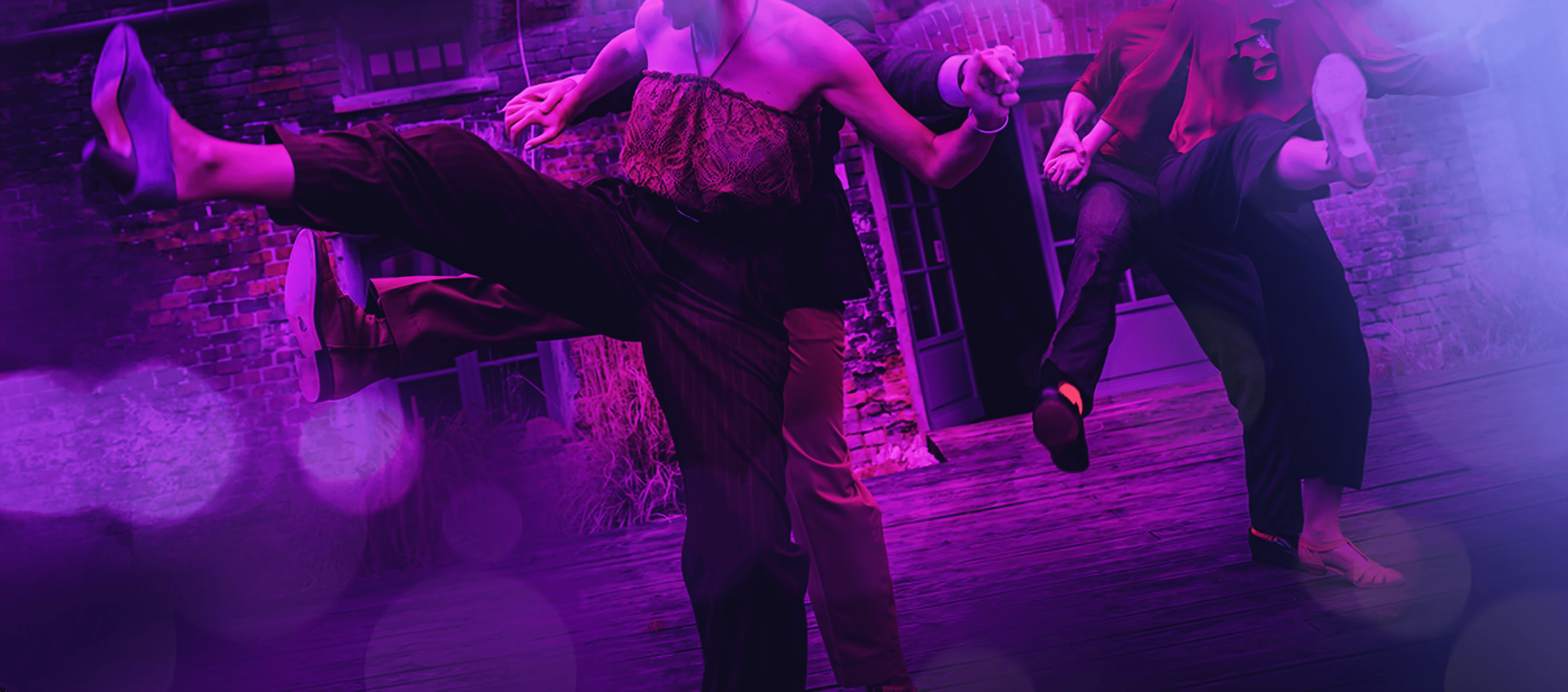 Three dancers performing on a purple-lit dance floor